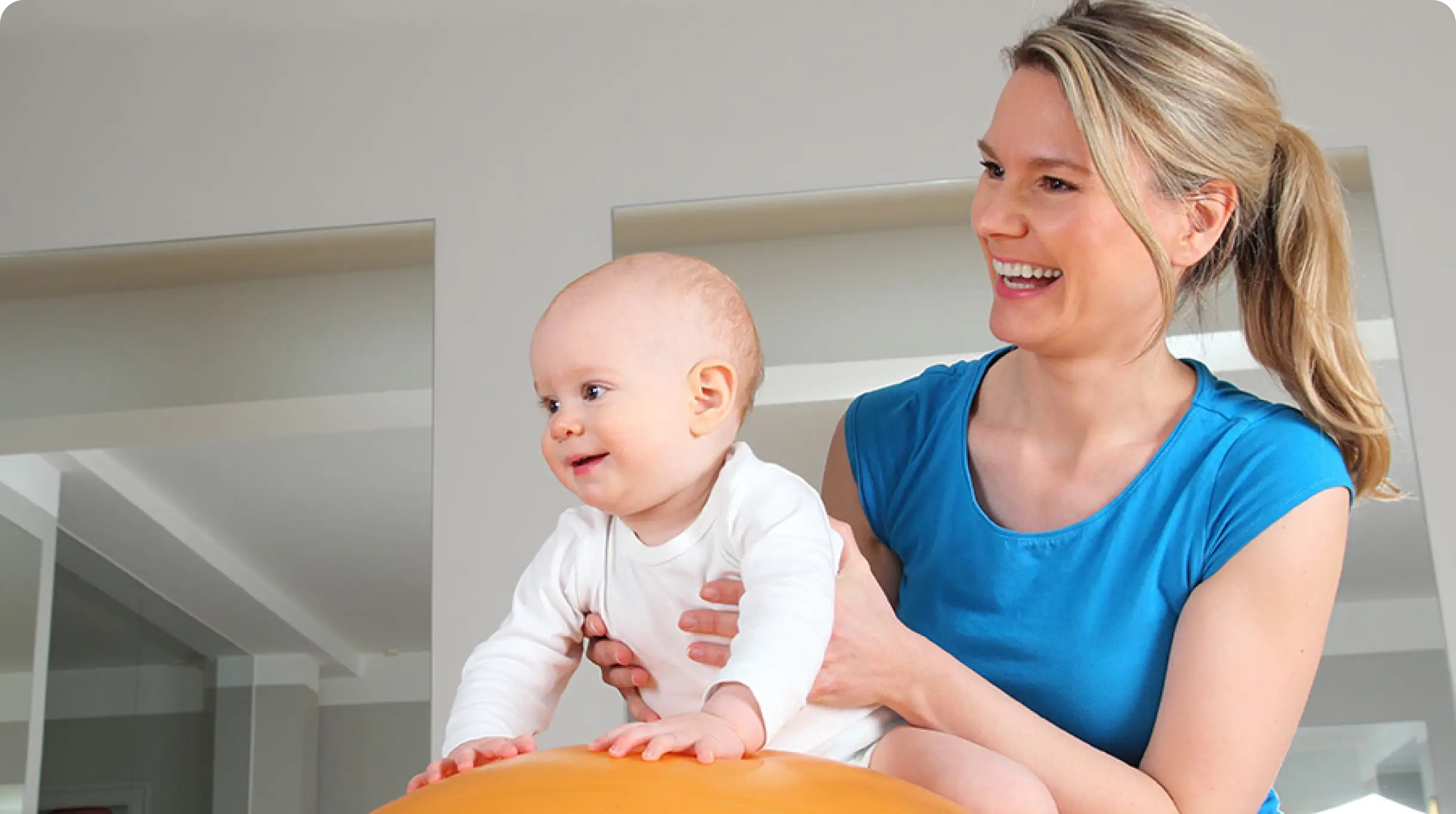 Smiling woman holding a baby in a bright room